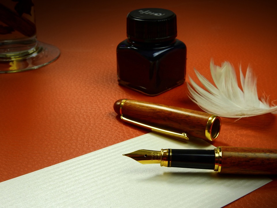 an old-fashioned quill pen, ink, and paper