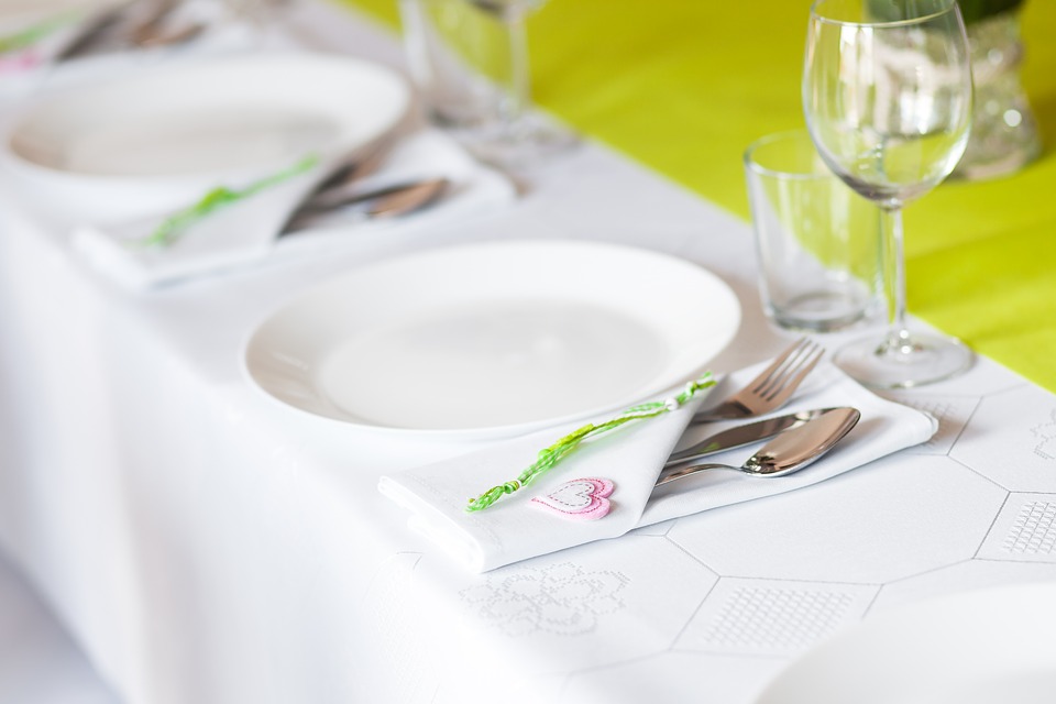 a place setting with a white plate, napkin, silverware, and glass