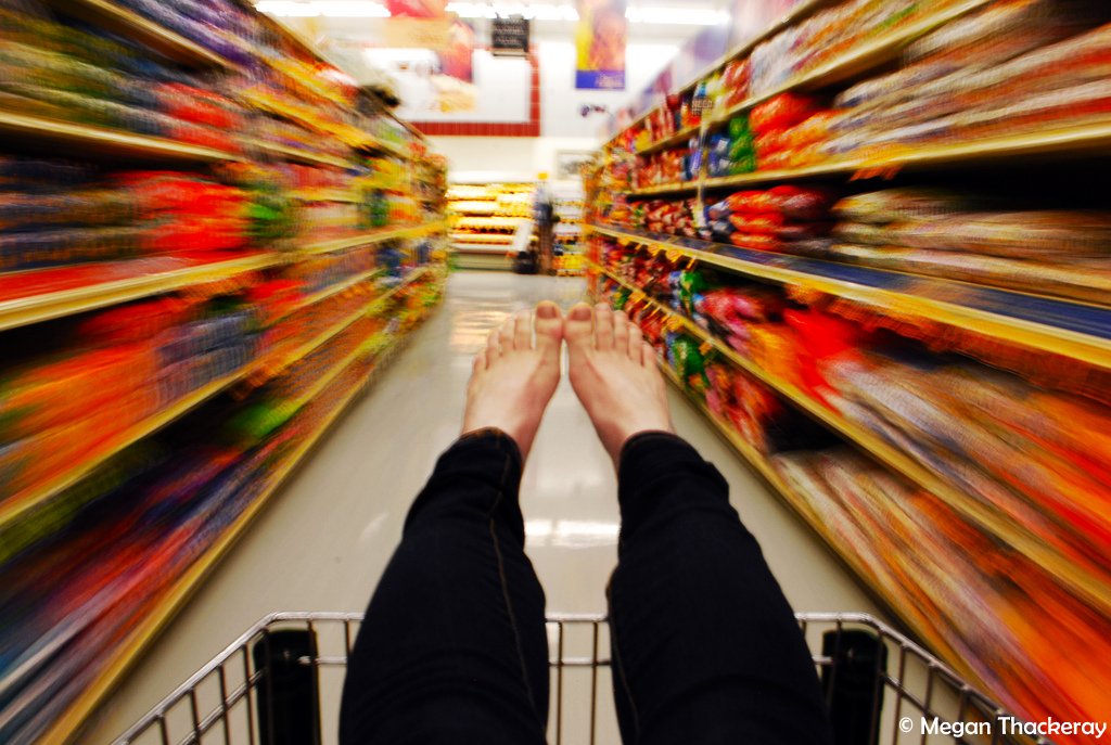 a person's feet sticking out of a grocery cart as they're being pushed down the aisle