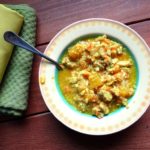 colorful stew served in a yellow bowl on a wooden table