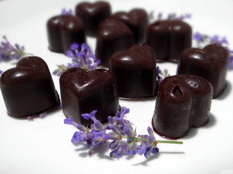 a plate of heart shaped chocolates with lavender blossoms artfully arranged around them