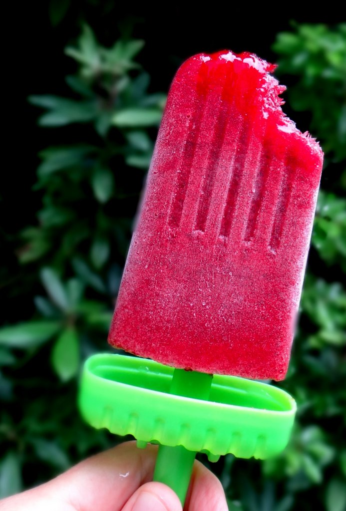 a kombucha berry popsicle with a bite taken out of the top