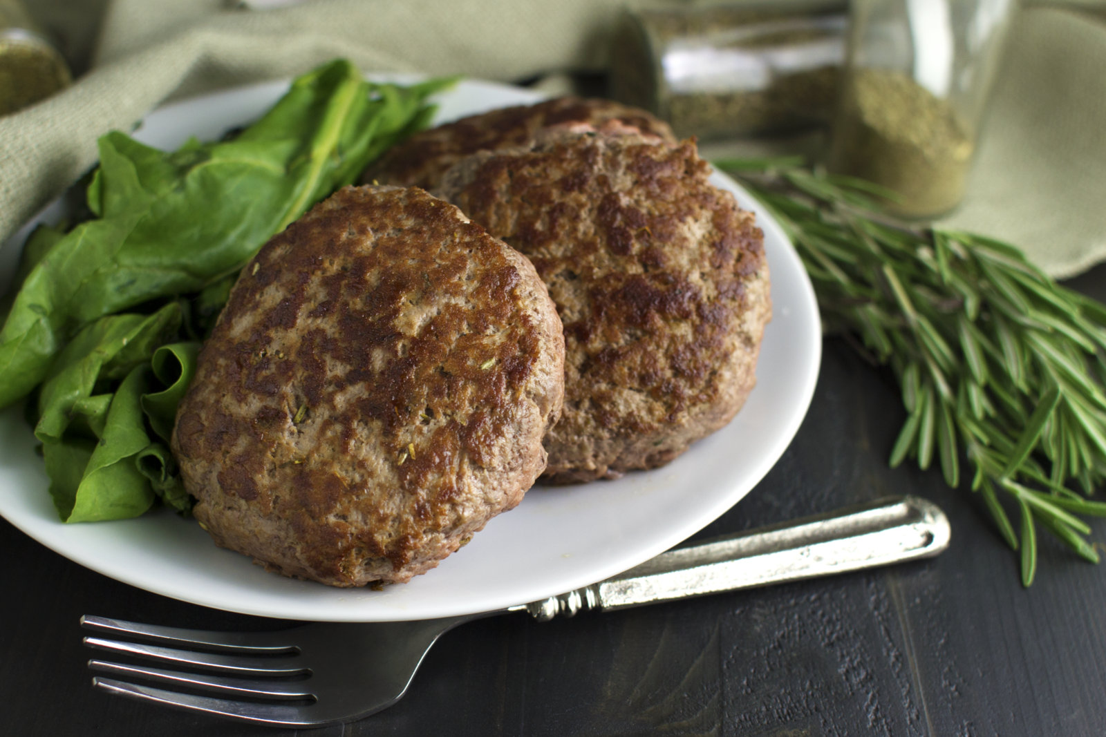 burgers on a plate with jars of herbs in the background