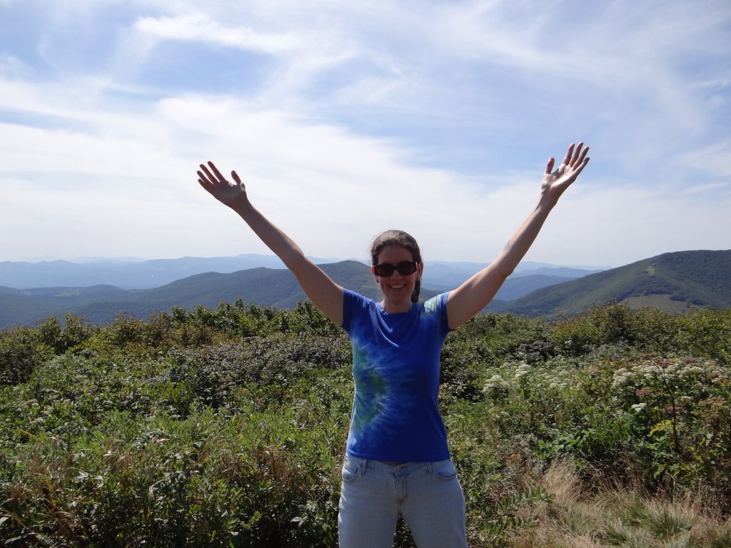 Eileen at the top of a mountain with her hands in the air, celebrating hiking again