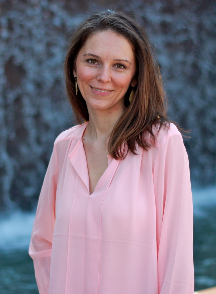 Angie smiling with long brown hair and wearing a pink shirt