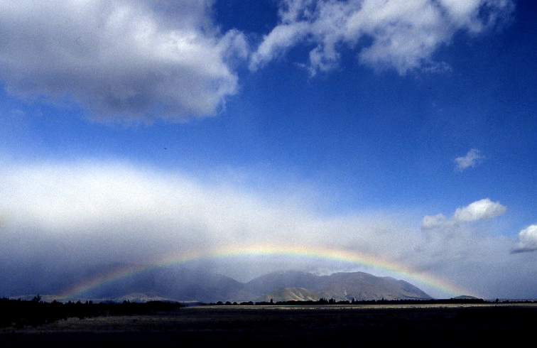 rainbow over a mountain range under a cloudy sky