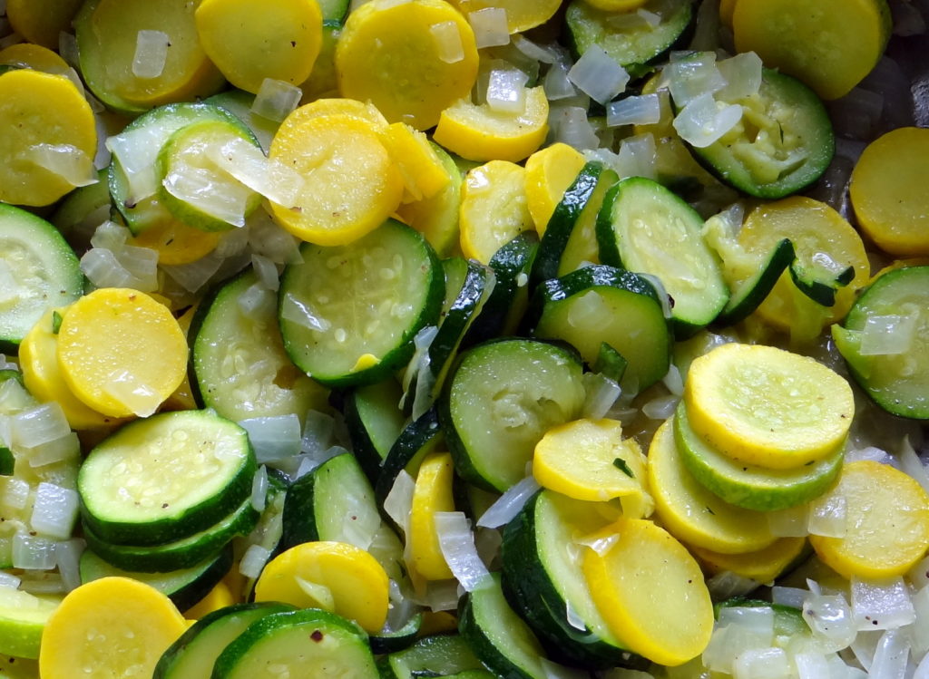 close-up photo of sliced zucchini and onion in the skillet