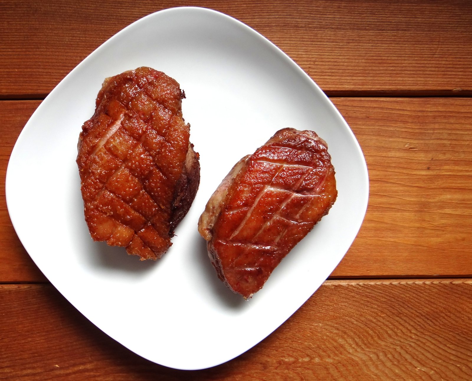 crispy duck breasts on a white plate