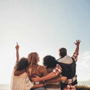 4 people with their arms around each other, arms raised