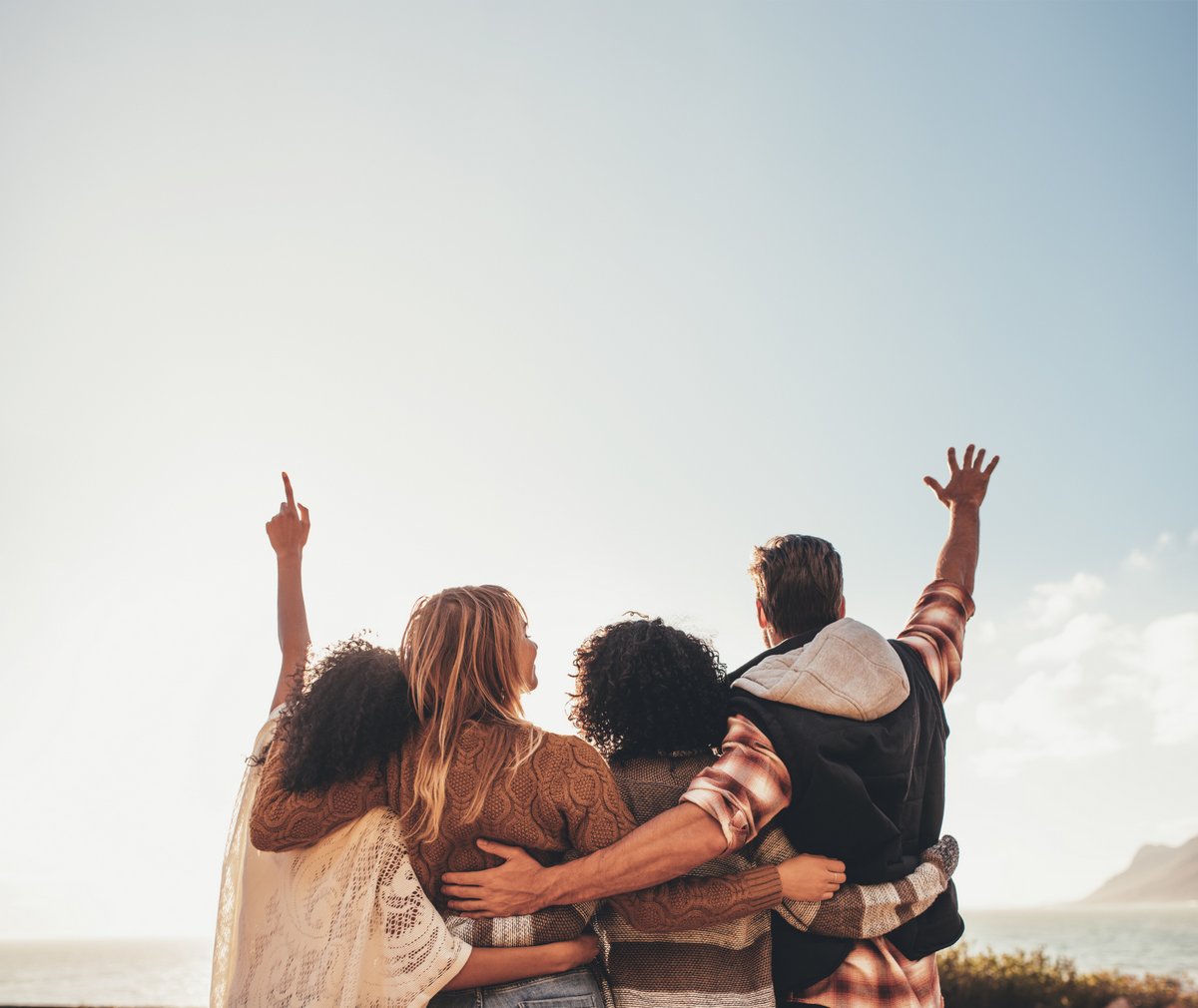 4 people with their arms around each other, arms raised