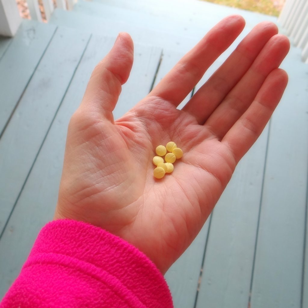 8 small yellow methotrexate pills held in the palm of her hand