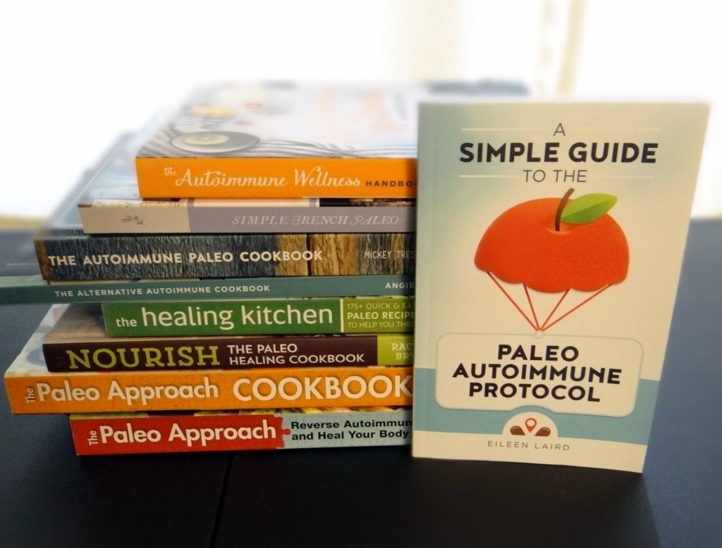 a stack of paleo AIP books and cookbooks