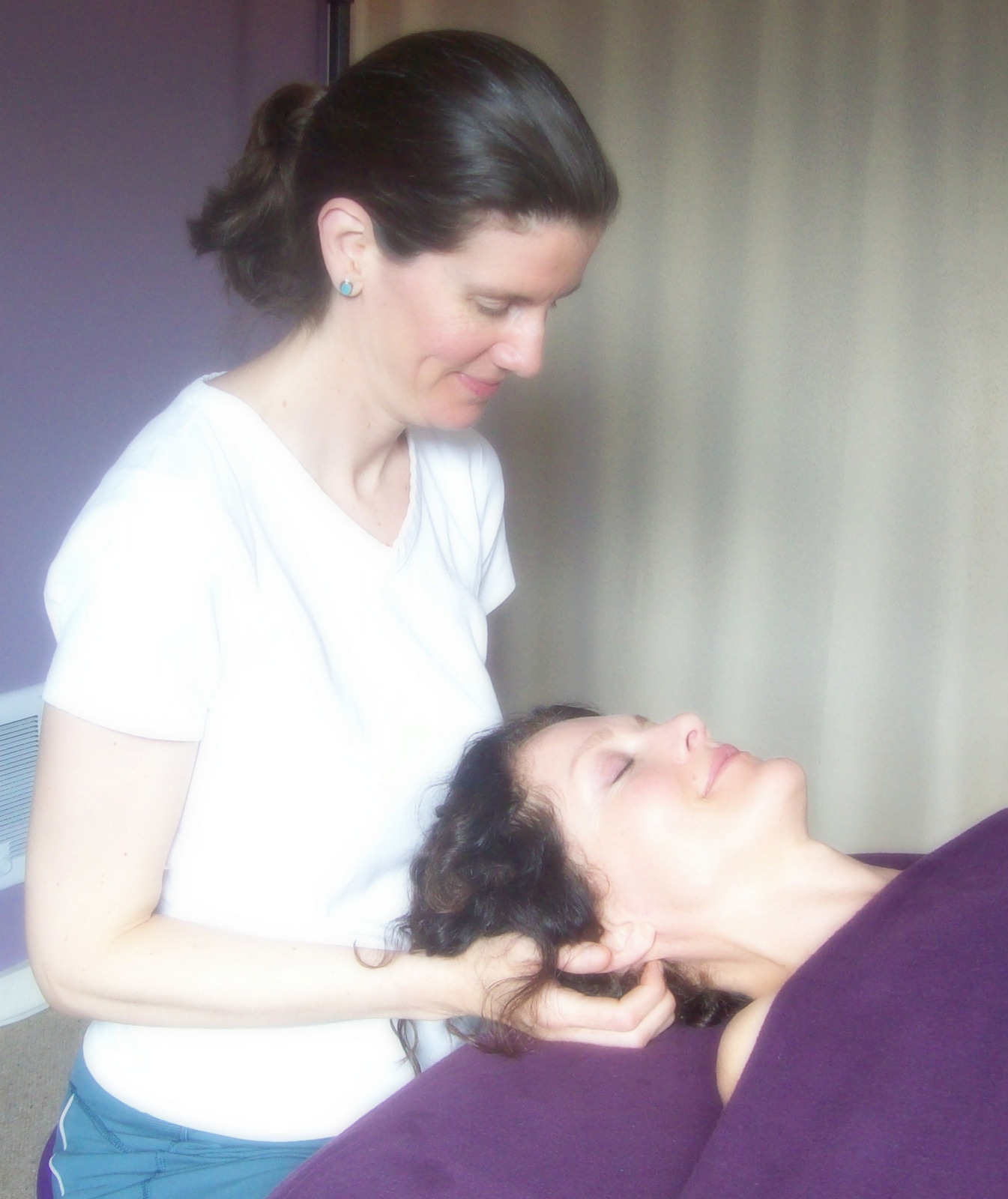 a woman lying on a massage table receiving a head massage