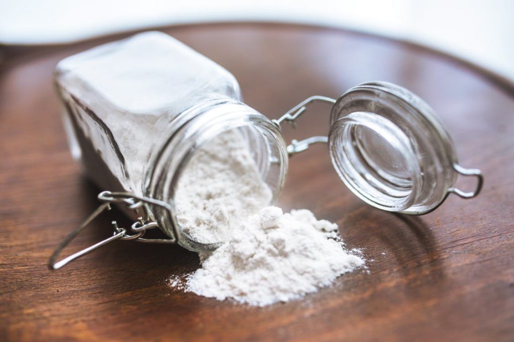 Jar of flour open and spilled on wooden surface