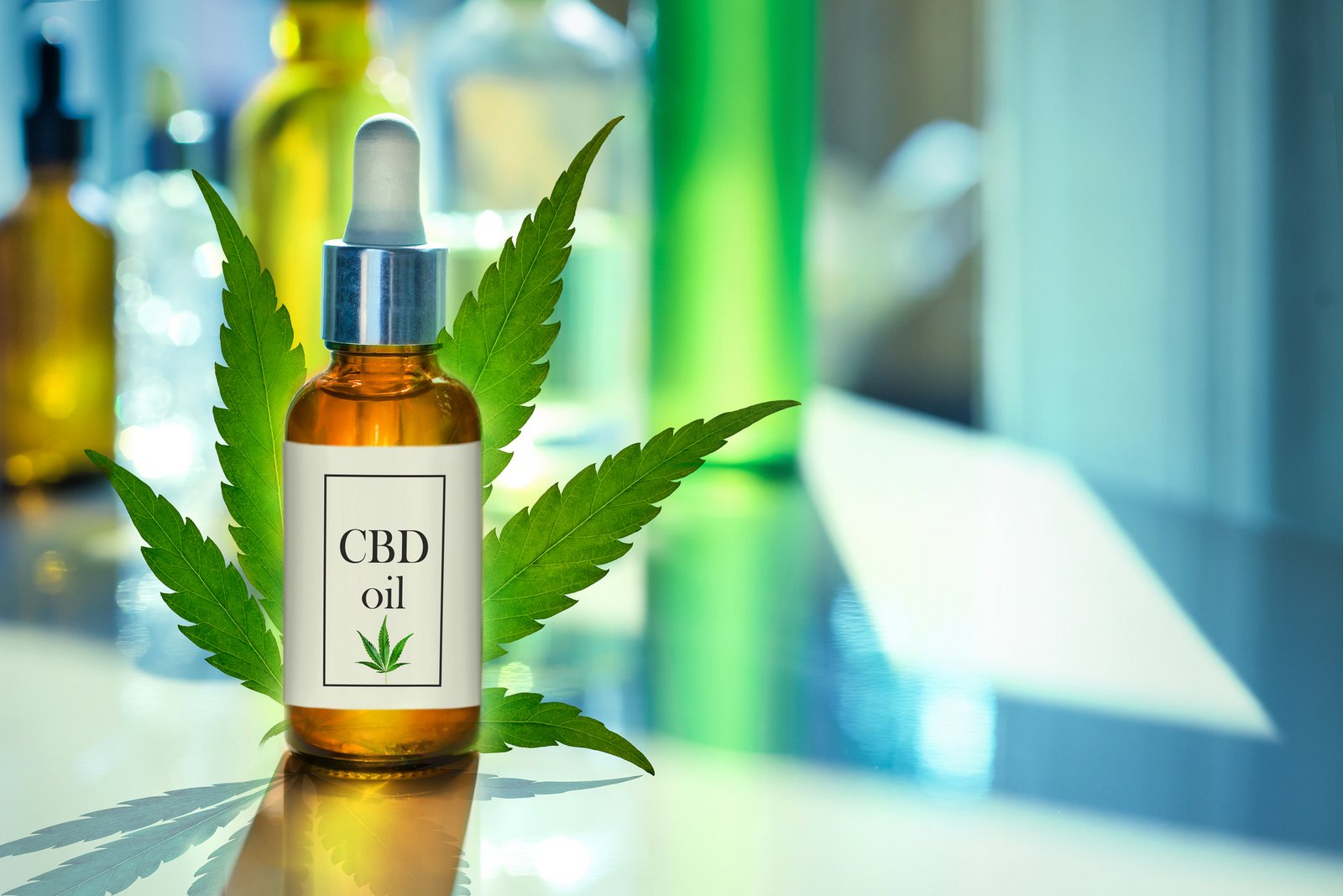 CBD oil bottle with hemp leaf behind it