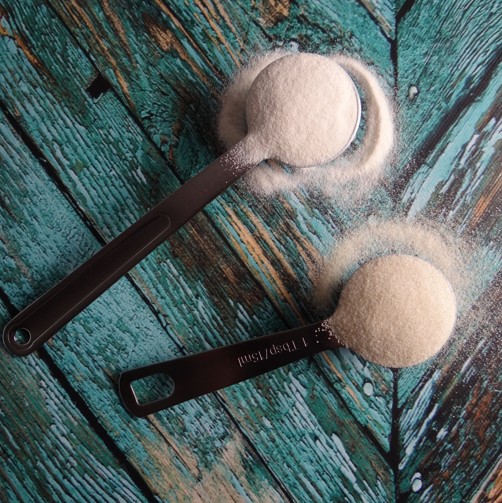 two measuring spoons, one filled with collagen and one with gelatin