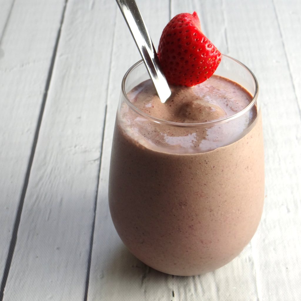 smoothie in a glass with a spoon and a strawberry on top