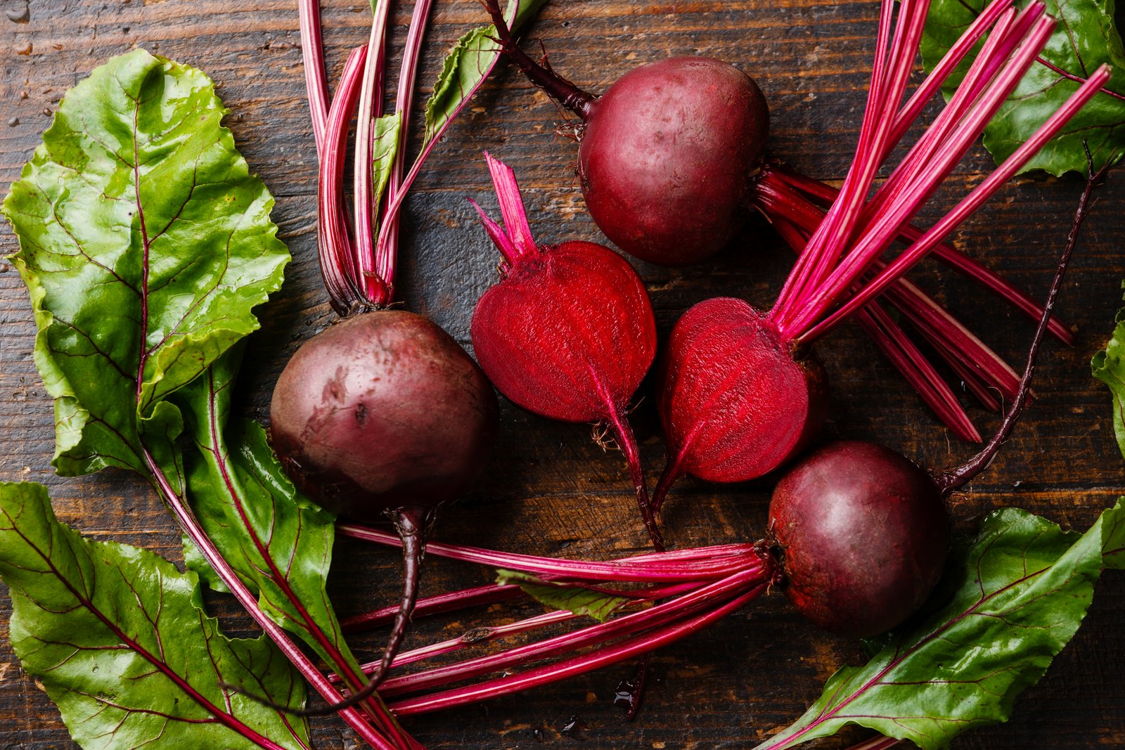 Red beets with stems and greens arranged on a cutting board