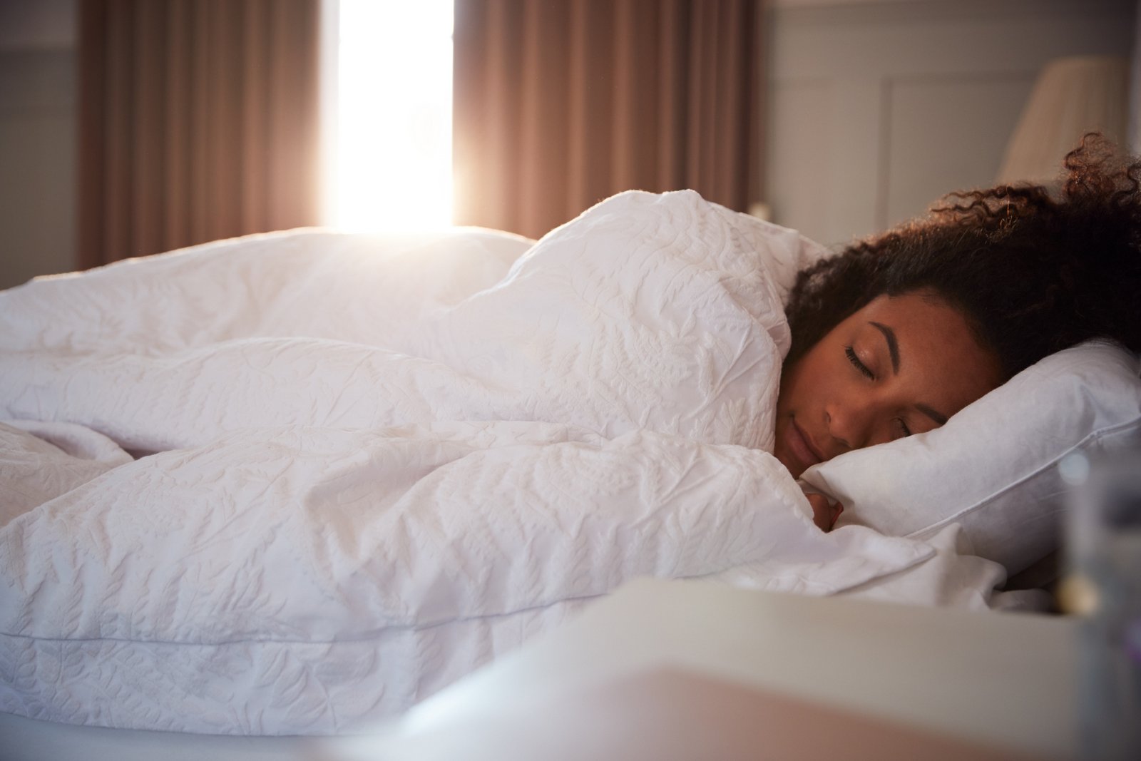 Woman sleeping with a fluffy white comforter and pillow