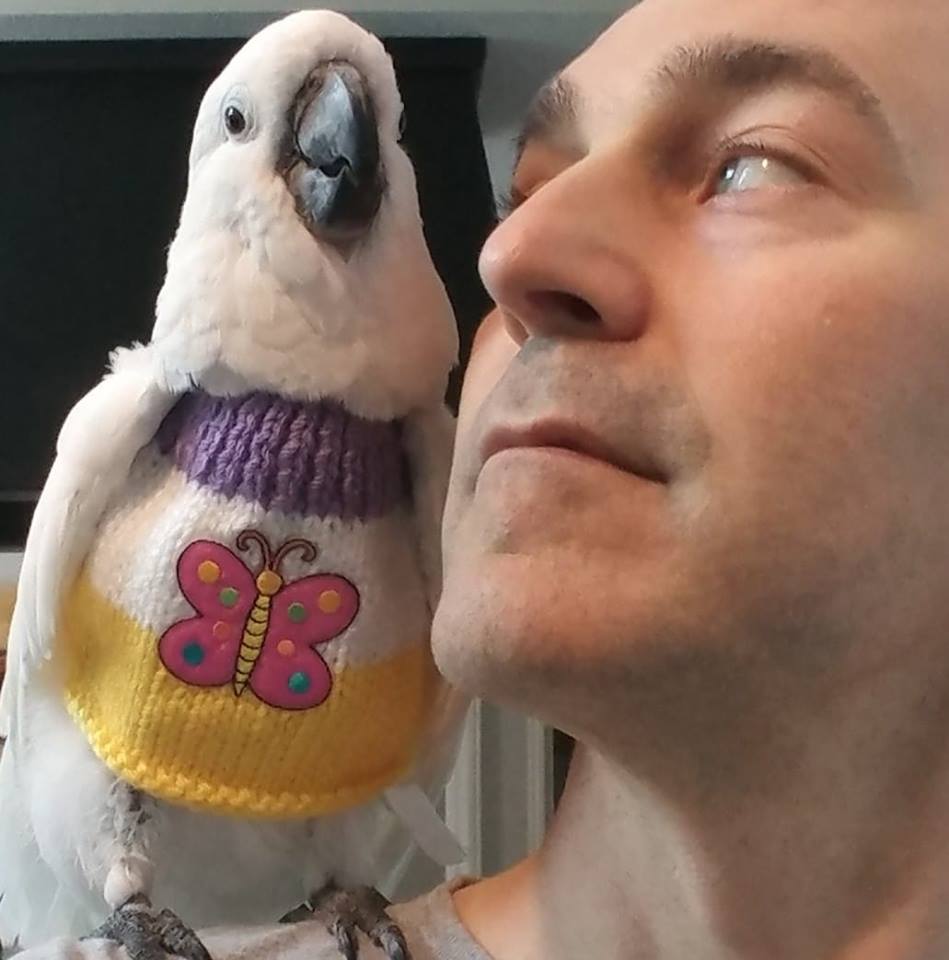 Dan with his white cockatoo (who is wearing a cute sweater)