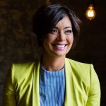 Jenny smiling with short black hair and a lime green leather jacket