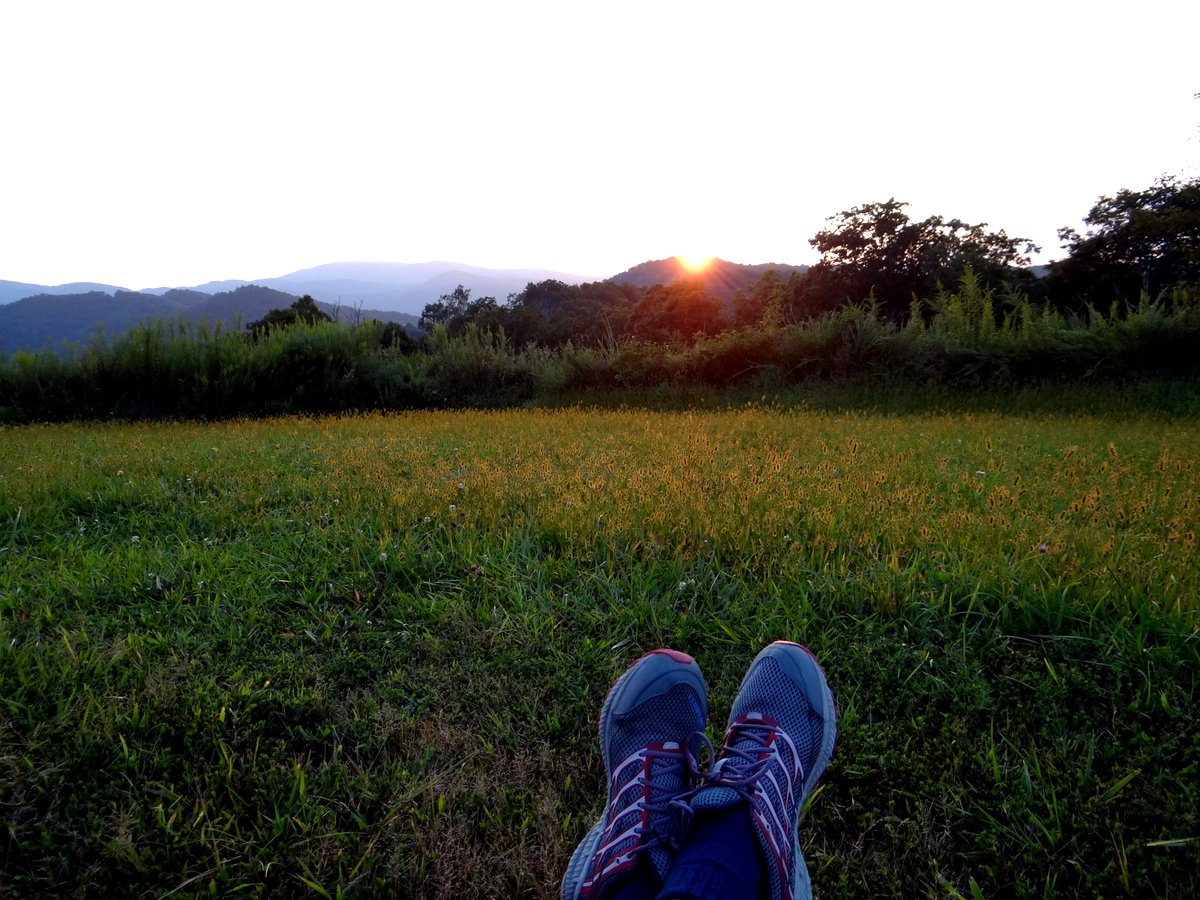 My crossed feet, relaxing in a field with mountain sunset in the background