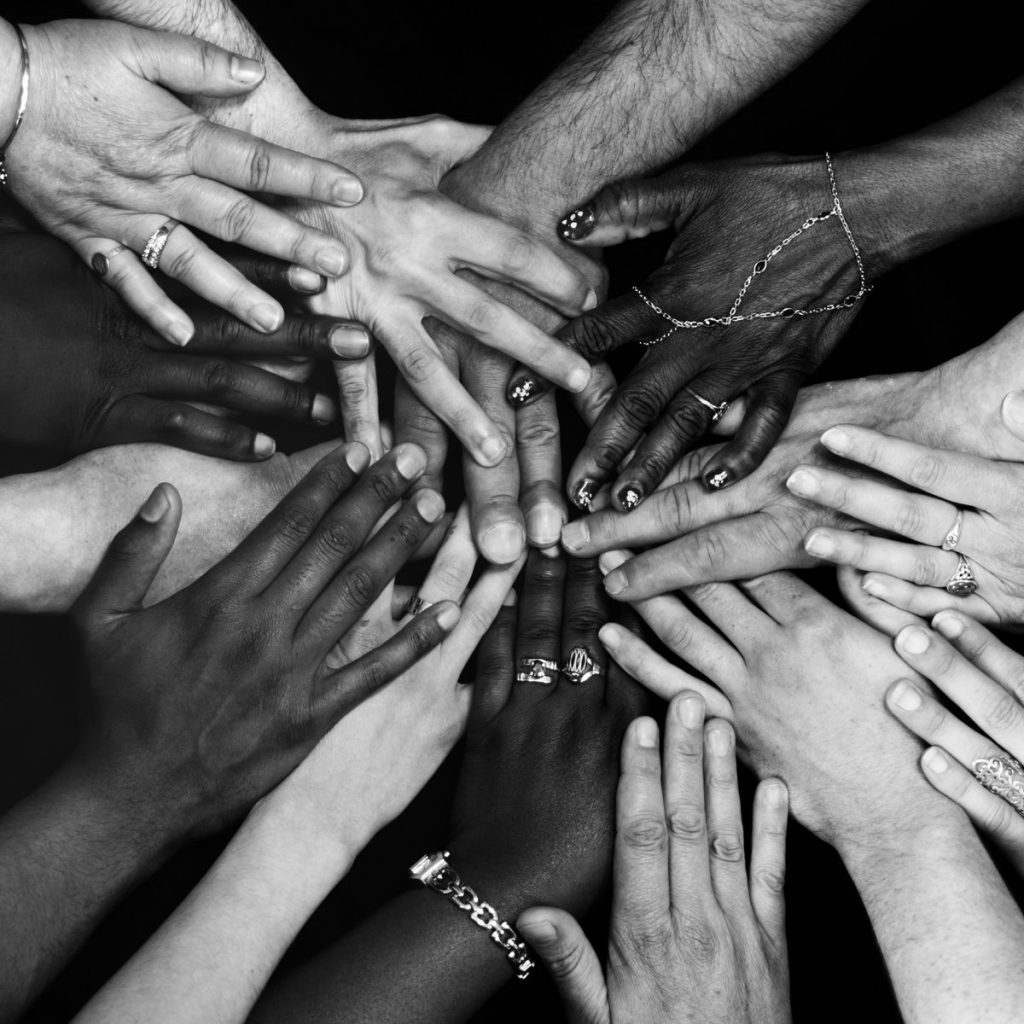 Hands of many different colors and ethnicities laid on top of each other representing unity and connection