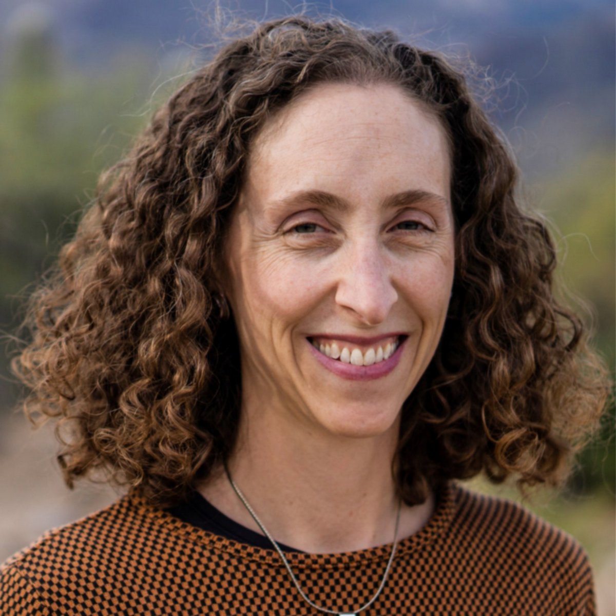 Lindsey with shoulder-length curly hair, smiling