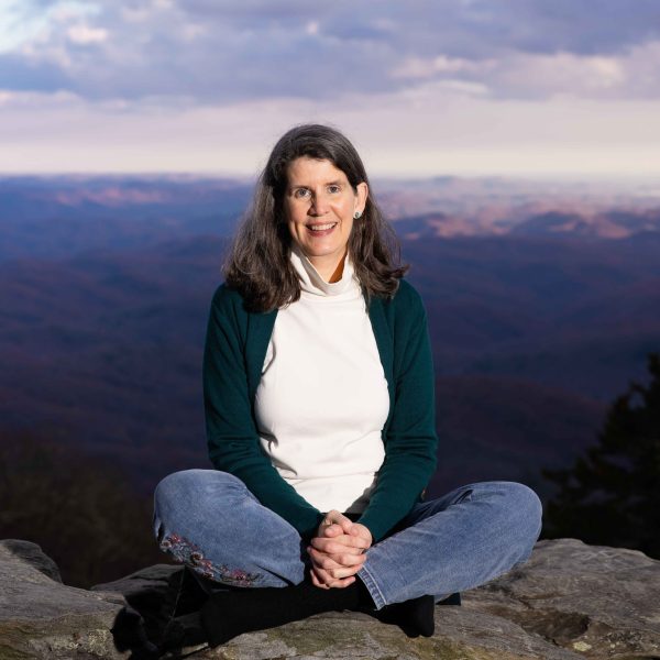 author smiling and sitting outside with legs crossed