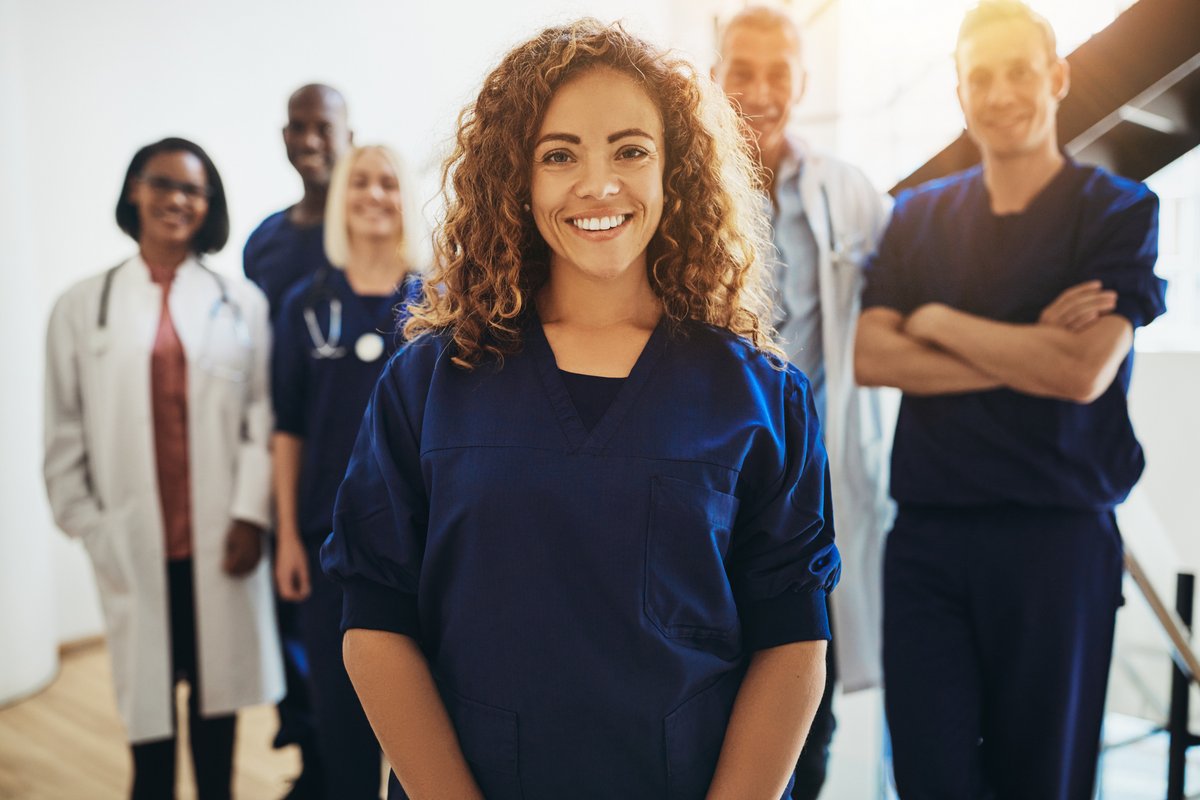 smiling female doctor with group of diverse doctors standing behind her