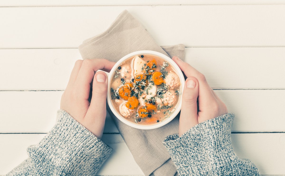 hands holding a bowl of soup