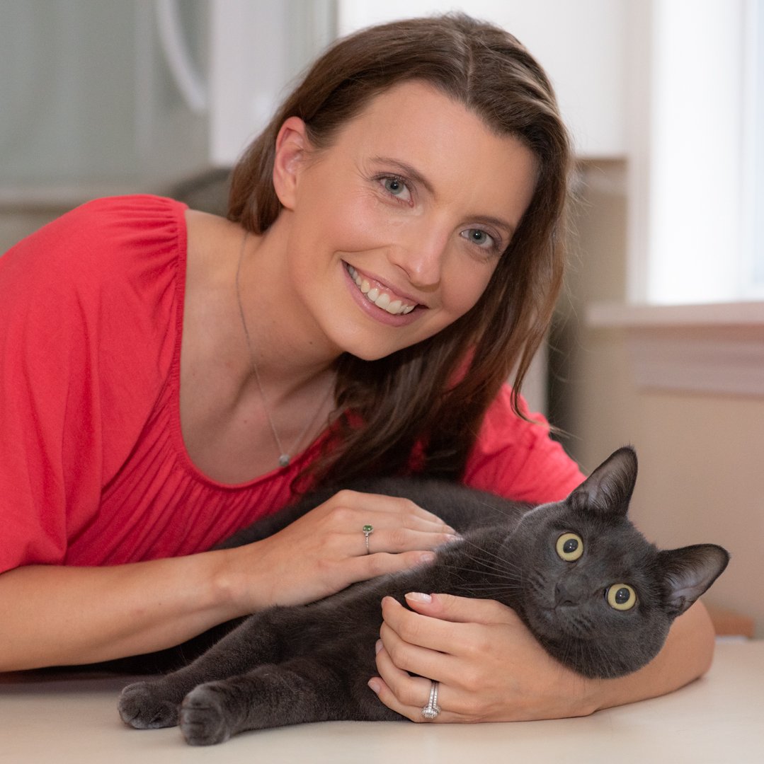 Alissa smiling as she pets her cat