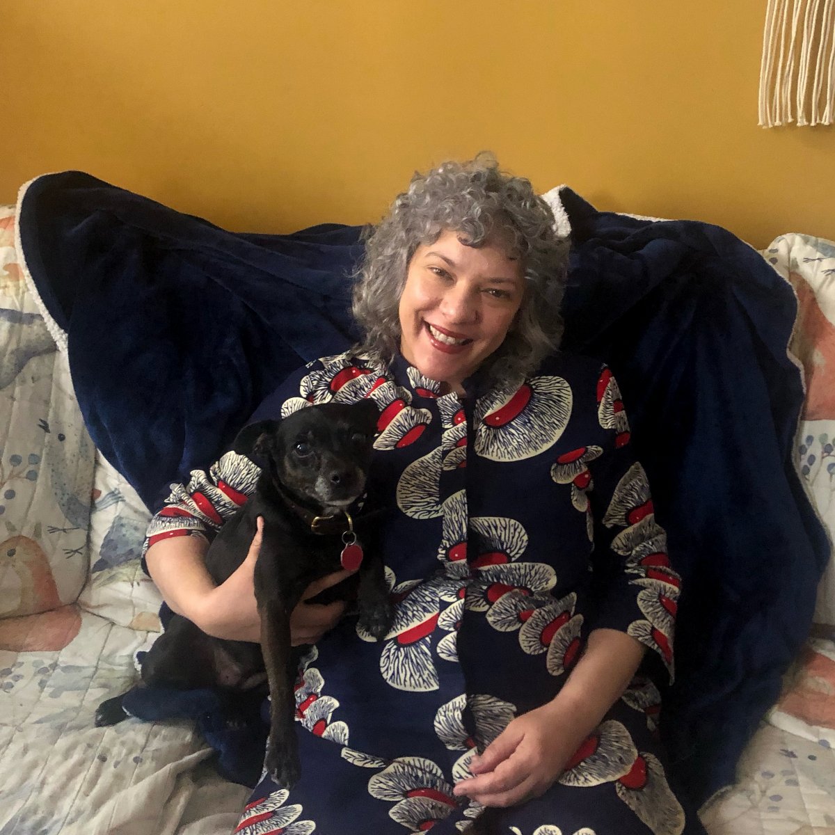 Isobeau smiling as she cuddles with her dog on the couch