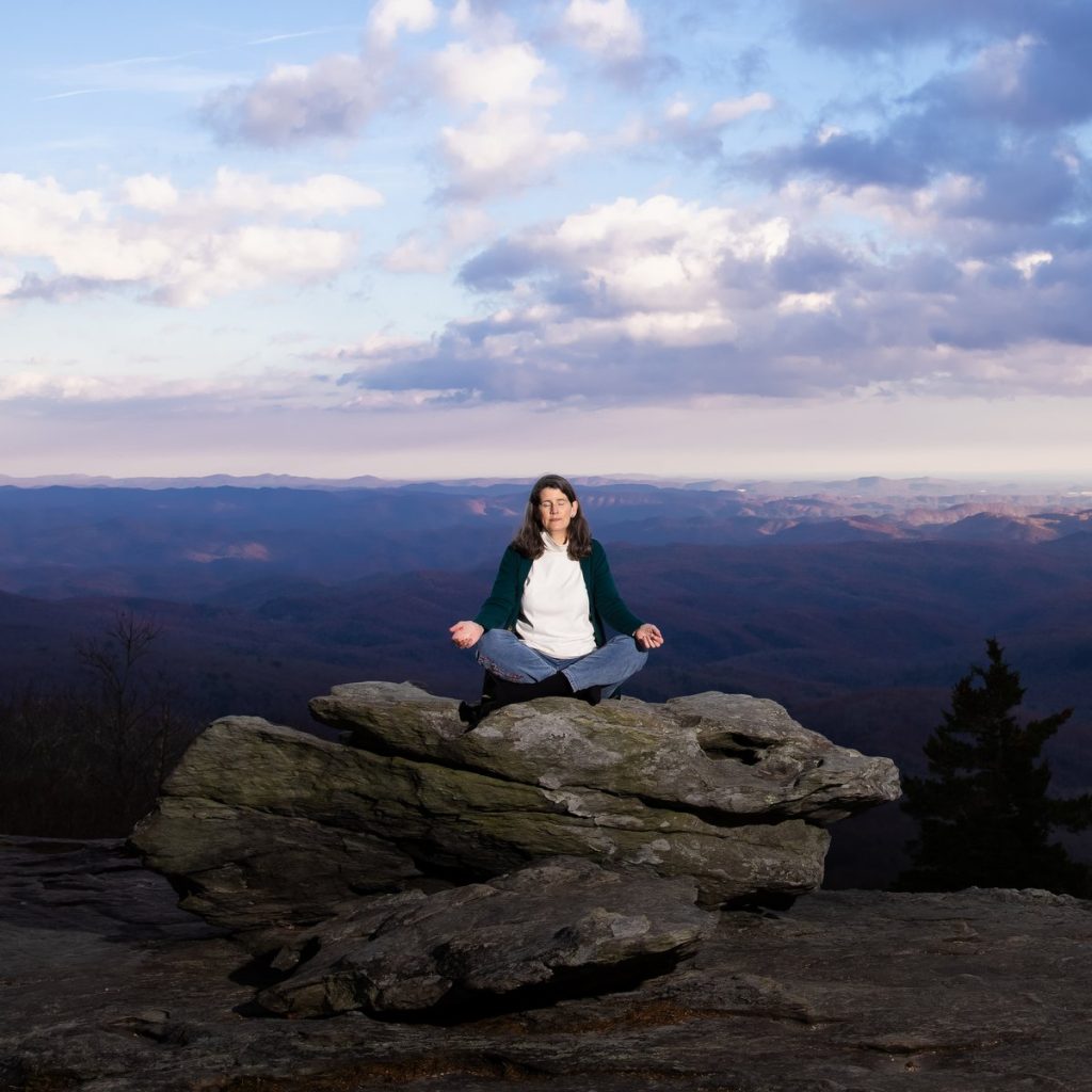 woman meditating outside with a mountain vista behind her