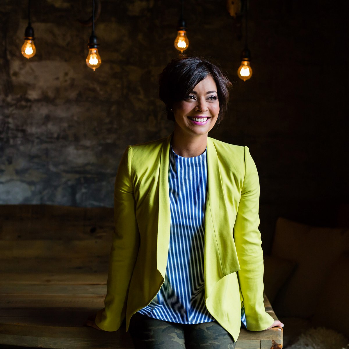 Jenny smiling with short black hair and a lime green leather jacket