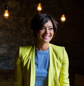 Jenny smiling with short black hair and a lime green leather jacket