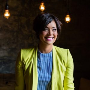 Jenny smiling with short black hair and a lime green leather jacket