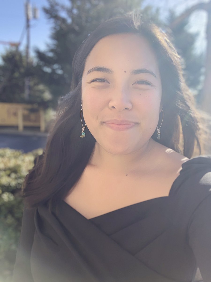 Emma smiling outside in filtered sunlight - long brown hair,