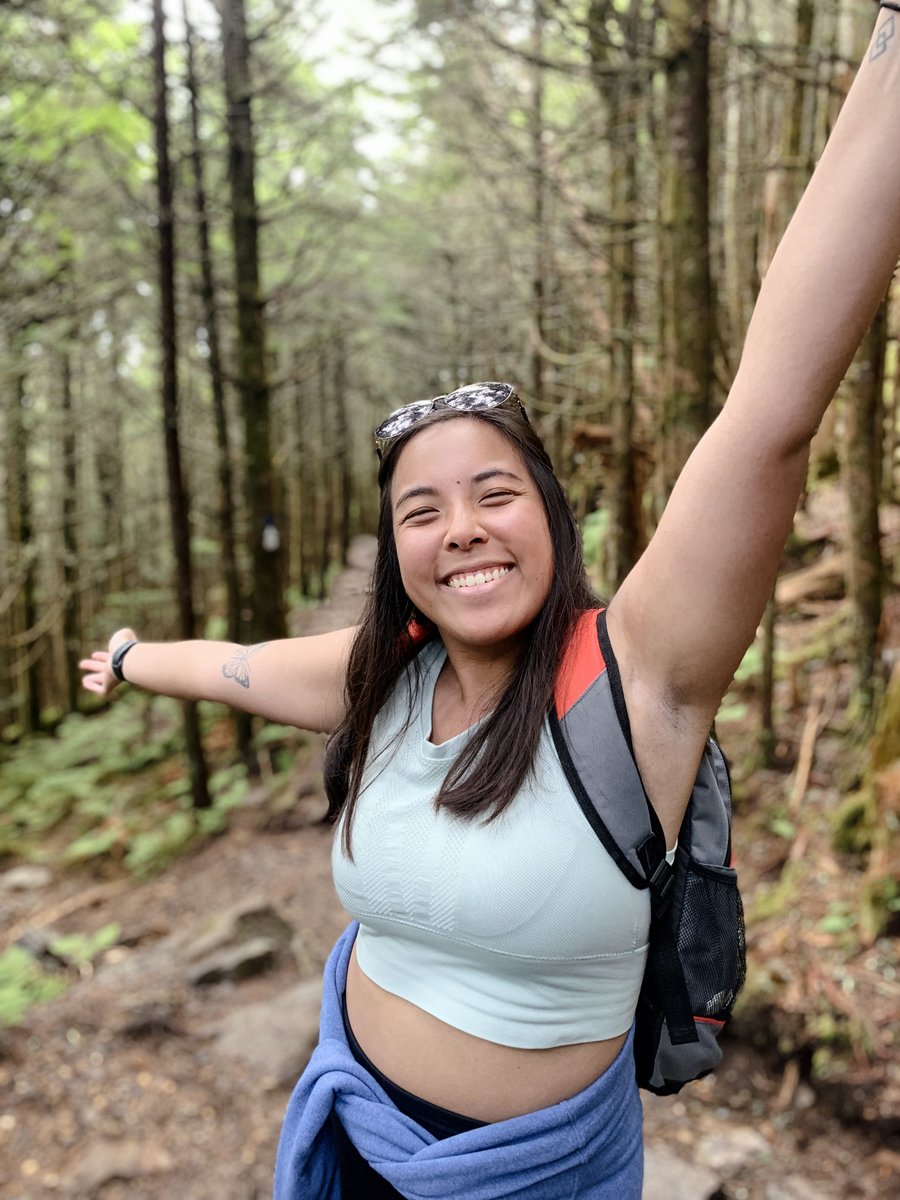 Emma hiking, arms raised and smiling big