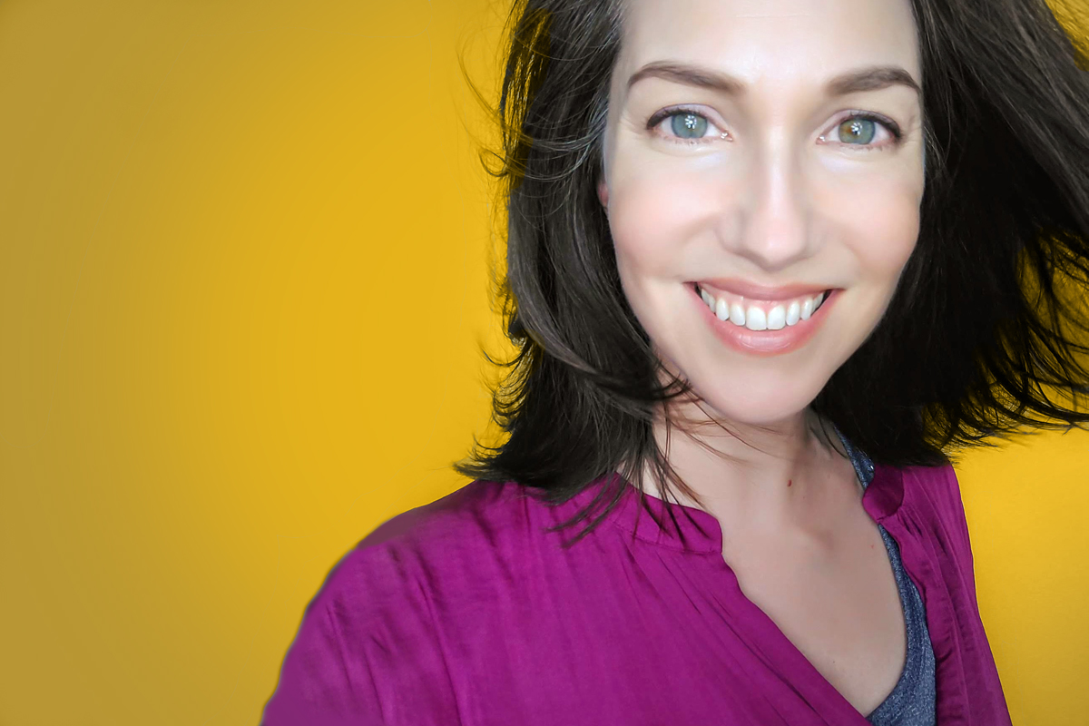 Sandy smiling with shoulder length brown hair and a bright purple shirt