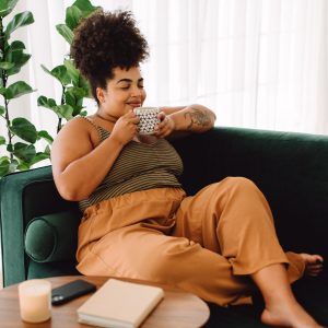 woman relaxing on couch and savoring a cup of tea