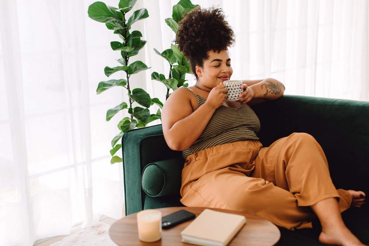 woman relaxing on couch and savoring a cup of tea