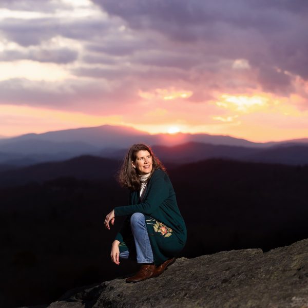 Eileen on a mountaintop, the sunset behind her