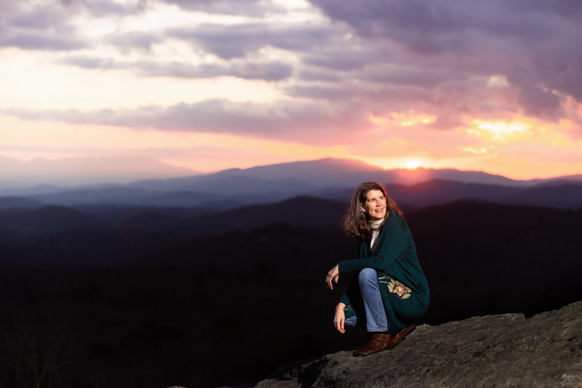 Eileen on a mountaintop, the sunset behind her