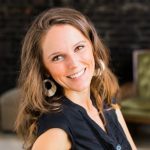 Angie smiling, wearing black shirt and dangling earrings